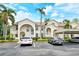 Beige two-story condo building featuring arched entryways, blue doors, well-maintained landscaping, and covered parking at 8315 Glenrose Way # 1421, Sarasota, FL 34238
