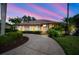 Charming home featuring a spacious driveway, lush landscaping, and elegant architectural details under a stunning sunset sky at 8321 9Th Avenue Nw Ter, Bradenton, FL 34209
