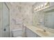 Classic bathroom with floral wallpaper, vanity, toilet, and enclosed tub with sliding door at 939 Sandpiper Cir, Bradenton, FL 34209
