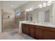 Bright bathroom featuring a tiled walk-in shower and double sink vanity with granite countertop at 9769 Highland Park Pl, Palmetto, FL 34221