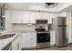 Modern kitchen with stainless steel appliances, white cabinets, and granite countertops at 104 Capri Isles Blvd # 207, Venice, FL 34292