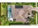 Aerial view of a home with solar panels, a screened pool, and lush tropical landscaping at 10523 Old Grove Cir, Bradenton, FL 34212