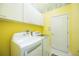 Bright laundry room with front load washer, dryer, overhead cabinets, and yellow walls at 10523 Old Grove Cir, Bradenton, FL 34212