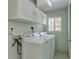 Well-lit laundry room with washer, dryer, overhead cabinets, and a window at 112 Palm Ave, Anna Maria, FL 34216