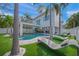 A beautiful backyard with a pool, spa, outdoor dining, lounge chairs and lush, tropical landscaping at 120 White Ave, Anna Maria, FL 34216