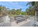 Outdoor deck with a dining table and seating with views of lush trees and a blue sky at 120 White Ave, Anna Maria, FL 34216