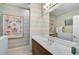 Bright bathroom featuring colorful striped wallpaper, vanity with white countertop, mirror, and tiled shower/tub at 12149 Forest Park Cir, Bradenton, FL 34211