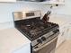 Close-up view of a stainless steel gas range and oven with stone countertops at 13156 Merlot Sunstone Cv, Parrish, FL 34219