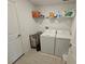 Laundry room featuring a washer, dryer, overhead shelving, and light tile flooring at 13156 Merlot Sunstone Cv, Parrish, FL 34219