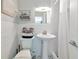 Bright bathroom features white subway tiles, pedestal sink, and toilet with stylish gray towels and toiletries at 170 Roosevelt Dr # 2, Sarasota, FL 34236