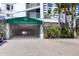 Garage entrance to Lido Harbour Towers with roll-up door, lush plants and a stone-accented wall at 1770 Benjamin Franklin Dr # 407, Sarasota, FL 34236