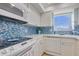 Bright kitchen featuring white cabinets, modern appliances, and blue tile backsplash at 1770 Benjamin Franklin Dr # 407, Sarasota, FL 34236