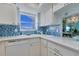 Well-lit kitchen features a double sink, modern appliances, and blue accent backsplash at 1770 Benjamin Franklin Dr # 407, Sarasota, FL 34236