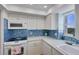 Bright kitchen featuring white cabinets, modern appliances, and a blue tile backsplash at 1770 Benjamin Franklin Dr # 407, Sarasota, FL 34236