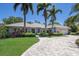 Beautiful single-story home with lush landscaping, palm trees, a paver driveway, and a two-car garage at 1780 Pine Harrier Cir, Sarasota, FL 34231