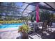 Screened pool with a patio table, chairs and pink umbrella, complemented by tropical landscaping, create an ideal outdoor oasis at 1780 Pine Harrier Cir, Sarasota, FL 34231