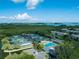 Aerial view of community tennis courts and pool surrounded by lush vegetation and the Sarasota Bay in the distance at 1780 Pine Harrier Cir, Sarasota, FL 34231
