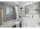 Bathroom features a tub, sink, modern fixtures, and elegant gray tile at 2438 Baywood W Dr, Dunedin, FL 34698