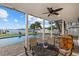 Covered patio with outdoor dining set, ceiling fan, and waterfront views of the pool and canal at 2438 Baywood W Dr, Dunedin, FL 34698
