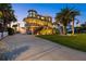 Inviting exterior elevation featuring a manicured lawn, a spacious driveway, and a beautifully lit home at 2438 Baywood W Dr, Dunedin, FL 34698