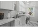 Well-lit laundry room featuring modern washer, dryer, sink, cabinets, and marble floors at 2438 Baywood W Dr, Dunedin, FL 34698