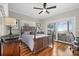 Comfortable bedroom boasts hardwood floors, a ceiling fan, and sliding glass doors to an outdoor deck with water views at 2438 Baywood W Dr, Dunedin, FL 34698