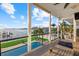 Spacious covered outdoor deck with comfortable seating offers water views, access to the dock, and lush landscaping at 2438 Baywood W Dr, Dunedin, FL 34698