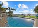 Inviting backyard swimming pool and jacuzzi offer a stunning view of the water, palm trees, and a white fence at 2438 Baywood W Dr, Dunedin, FL 34698