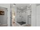 Modern glass shower adorned with designer tiles and contrasting black hexagonal base, complemented by an open door at 2438 Baywood W Dr, Dunedin, FL 34698