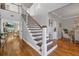 Bright foyer showcasing staircase with hardwood steps and decorative iron railing leading to the upper level and hardwood floors at 2438 Baywood W Dr, Dunedin, FL 34698