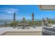 An amazing water view from the balcony with two umbrellas, chairs, and a stylish brown and beige outdoor rug at 420 Golden Gate Pt # 200A, Sarasota, FL 34236