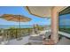 Exterior balcony featuring tiled floors, upscale lounge chair, sun umbrella, and picturesque waterfront view at 420 Golden Gate Pt # 200A, Sarasota, FL 34236