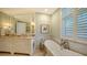 This elegant bathroom featuring a soaking tub, shuttered windows and double sink vanity has refined, classic style at 420 Golden Gate Pt # 200A, Sarasota, FL 34236