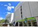 Modern building exterior with large windows and the Lemon Tree Kitchen entrance, enhanced by palm trees and blue skies at 420 Golden Gate Pt # 200A, Sarasota, FL 34236