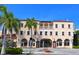 Elegant building with arched entryways, a Juliet balcony, and palm trees at 420 Golden Gate Pt # 200A, Sarasota, FL 34236