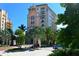 Elegant condo building exterior surrounded by lush landscaping and mature palm trees on a sunny day at 420 Golden Gate Pt # 200A, Sarasota, FL 34236