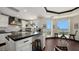 Modern kitchen with white cabinets, black countertops, and island seating with stools, offering a beautiful water view at 420 Golden Gate Pt # 200A, Sarasota, FL 34236