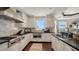 Chef's kitchen featuring stainless steel appliances, including a range hood, and quartz countertops, offering water views at 420 Golden Gate Pt # 200A, Sarasota, FL 34236