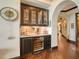 Elegant wet bar featuring glass-front cabinets, a wine cooler, and decorative backsplash at 420 Golden Gate Pt # 200A, Sarasota, FL 34236