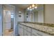 Bathroom featuring a long vanity with granite countertops, white cabinets, and a well-lit mirror at 4420 Exeter Dr # L104, Longboat Key, FL 34228
