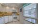 Well-lit kitchen featuring granite countertops, white cabinets and appliances, and mosaic tile backsplash at 4420 Exeter Dr # L104, Longboat Key, FL 34228