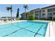 Community swimming pool with clear blue water, palm trees, and stunning waterfront views at 4420 Exeter Dr # L104, Longboat Key, FL 34228
