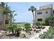 Well-maintained condo exterior with landscaping, palm trees, and view of the pool in background at 4621 Gulf Of Mexico Dr # 2F, Longboat Key, FL 34228