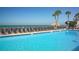 Inviting community pool with clear blue water, palm trees, and lounge chairs overlooking the ocean at 4621 Gulf Of Mexico Dr # 2F, Longboat Key, FL 34228