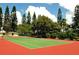 Well-maintained community tennis court with green playing surface and surrounding pine trees at 4621 Gulf Of Mexico Dr # 2F, Longboat Key, FL 34228