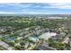 Community aerial view showcasing tennis courts, lake, and buildings amid lush green landscape at 4802 51St W St # 1711, Bradenton, FL 34210