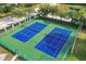 Aerial view of two well-maintained blue and green tennis courts surrounded by lush landscaping at 4802 51St W St # 1711, Bradenton, FL 34210