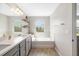 Bathroom with double sink vanity, large mirror, soaking tub, and decorative shelving at 5007 Sunnyside Ln, Bradenton, FL 34211