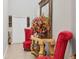 Elegant foyer with decorative mirror, ornate table with floral arrangement, and stylish red armchairs at 5033 Brickwood Rise Dr, Wimauma, FL 33598