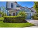 Charming blue two-story home features a well-manicured lawn, mature bushes, and a two-car garage at 5033 Brickwood Rise Dr, Wimauma, FL 33598
